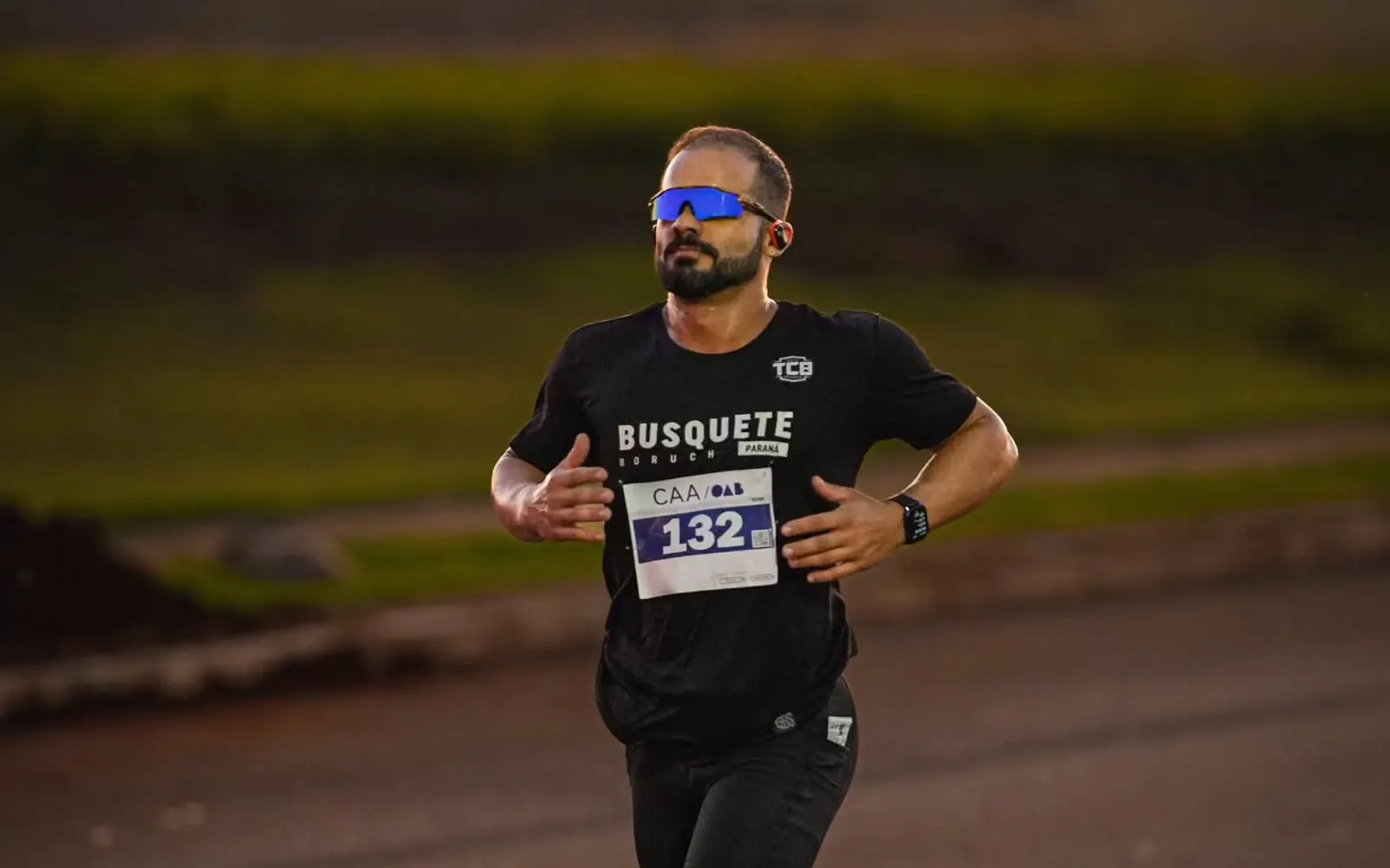 Atleta correndo no fim da tarde, com número de prova